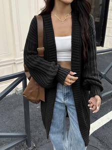 Stile street outdoor con un cardigan lungo in maglia nera abbinato a jeans in denim