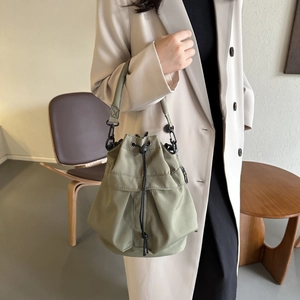 Détail du sac seau vert armée avec fermeture à cordon et accents métalliques sur modèle