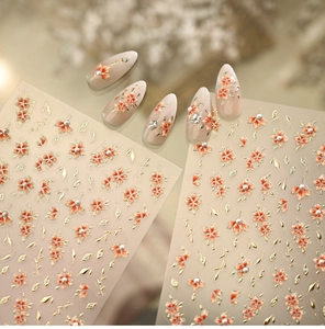 Macro detail of 3D embossed floral nail stickers with pink petals and metallic leaves