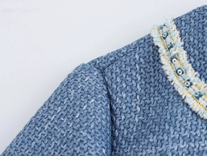 Makroaufnahme von Tweedkleid-Schulter mit blauen Pailletten und edlen Perlendetails