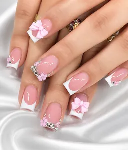 Macro detail of French press-on nails with pink 3D bows and sparkling rhinestones