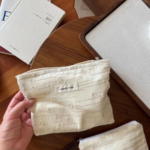 Detailed view of the textured linen makeup bag featuring a simple wish woven label