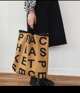 Detail of camel canvas tote bag with bold black minimalist lettering and sturdy handles