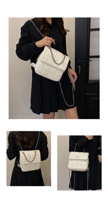 Detail of white quilted chain bag featuring a heart-shaped relief and metal shoulder strap