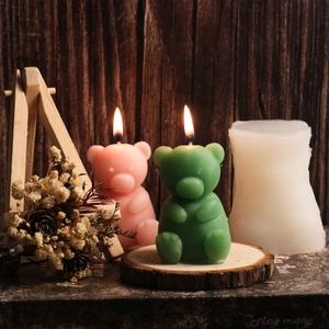 Detail of cute sitting bear silicone candle mold with finished pink and green wax samples