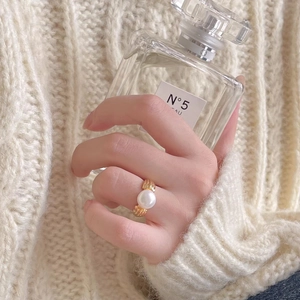 Macro detail of gold-plated ribbed ring with a large white pearl on wool background