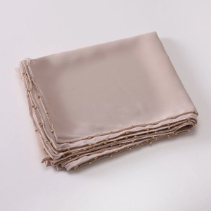 Detail of nude pink faux silk hijab featuring delicate gold bead chain trim on the edge