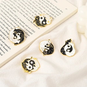 Detail view of five yin yang enamel pins featuring koi and animals on a book background