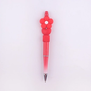 Close-up of a red DIY beaded pen with a floral silicone charm and glitter finish