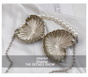 Macro detail of silver heart shell evening bag with magnetic clasp and radial texture