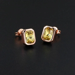 Macro shot of rose gold rectangle stud earrings with yellow step-cut zircon stones
