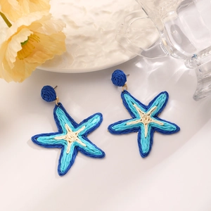 Detail of bohemian raffia woven starfish earrings with vivid blue and cream color layers