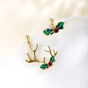 Detail of Christmas reindeer antler earrings with holly leaf and red gemstone accents
