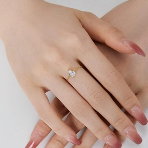 Close-up of adjustable gold chain ring with a sparkling water-drop shaped zircon on finger