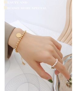 Detail of 18K gold beaded bracelet with coin pendant and elegant pearl ring on a model