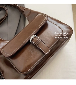 Detailed macro view of brown oil wax leather shoulder bag with metallic buckle and stitching