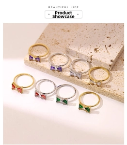 Detail view of bow-shaped gemstone rings in gold and silver finish on stone tray