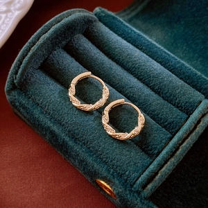 Minimalist gold-plated twisted hoop earrings with zircon stones on green velvet box