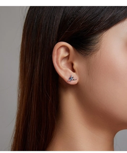 Close-up of a colorful dragonfly stud earring with vibrant gems on a female model's ear