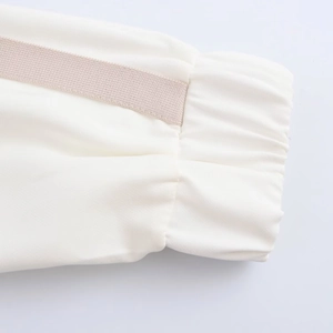 Detailed macro view of white sleeve cuff with elastic band and beige decorative ribbon