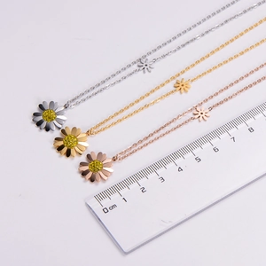 Three-color daisy pendant necklaces shown with a ruler for size reference and scale