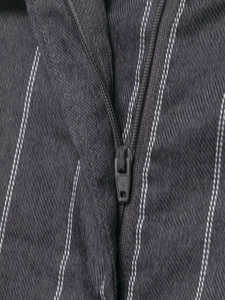 Close-up of high-quality metal zipper and striped dark gray fabric on suit trousers