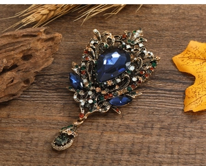 Detail of vintage bronze water-drop brooch with blue stones and hollow floral design