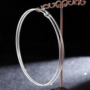Detailed view of large polished silver hoop earrings on a vintage display stand