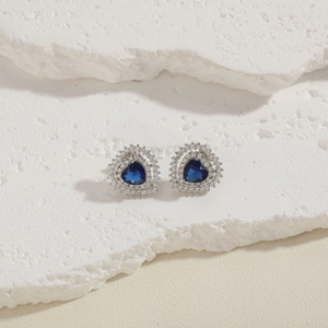 Detail of heart-shaped blue zircon earrings with silver double halo on stone base