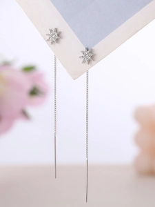 Macro view of silver star tassel earrings with zircons on elegant white background