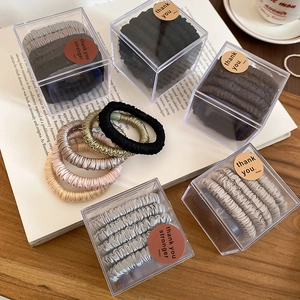 Set of five silk-like elastic hair scrunchies in neutral tones inside a clear gift box