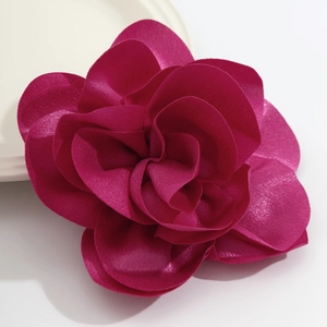 Close-up of elegant magenta fabric rose brooch with silk luster and layered petals