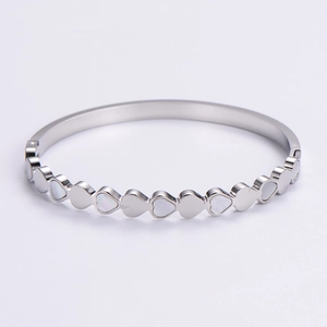 Detail of silver heart link bracelet with white shell inlay and polished metal finish