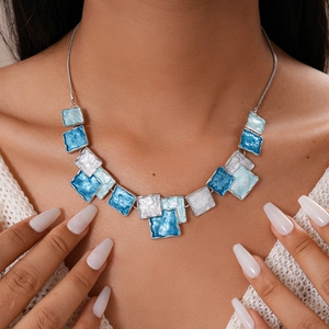 Detail of blue and white geometric enamel squares on a silver chain necklace