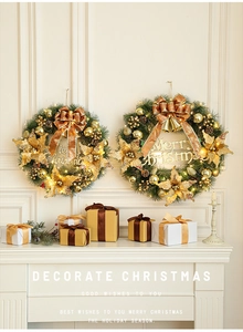 Close-up of lighted Christmas wreath with golden bows on a fireplace mantel