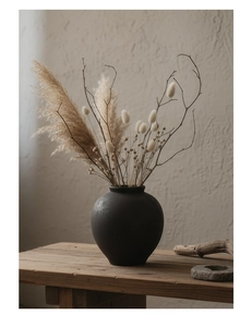 Détail du vase en céramique noir mat avec fleurs séchées sur table bois rustique