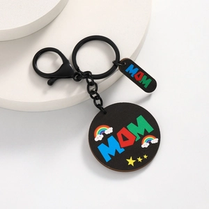 Wooden Mother's Day keychain with MOM rainbow lettering and black metal clip on white stand