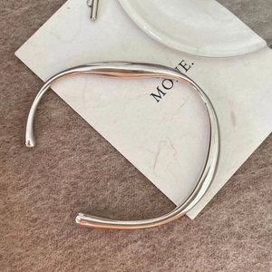 Macro detail of 925 sterling silver solid bangle with irregular fluid stream design