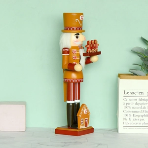 Gingerbread themed chef nutcracker figurine with yellow finish and festive house base