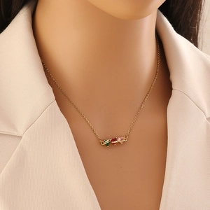 Fashionable gold necklace with three colorful heart gemstones worn by model in beige blazer