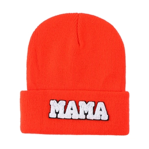 Detail of bright orange knit beanie featuring white towel-embroidered MAMA lettering