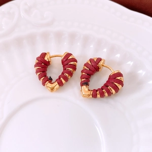 Detail of 18k gold heart hoop earrings with burgundy braided rope texture on ceramic