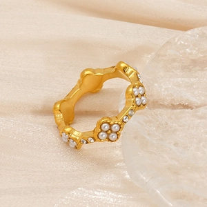 Close-up of 18K gold wave ring featuring inlaid pearls and sparkling cubic zirconia crystals