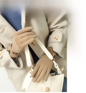 Detail of khaki thermal gloves featuring a decorative metal chain and leather strap buckle