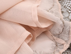 Dettaglio del pizzo rosa e del tessuto in chiffon testurizzato sull'abito