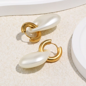 Detail shot of matte gold stainless steel earrings with fluid white acrylic pearl pendants