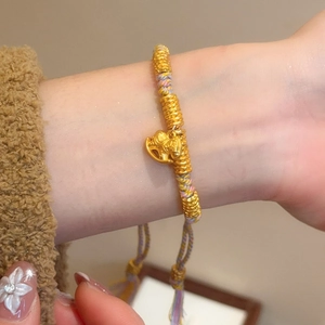 Close-up of woven silk bracelet with golden rocking horse pendant and tassel detail