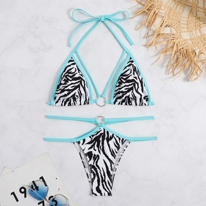 Blue-trimmed zebra print bikini set with metal rings and tie straps on marble backdrop