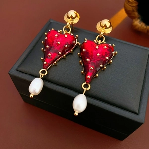 Detailed shot of red heart stud earring with golden textures and white pearl drop
