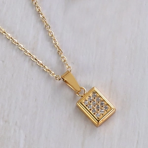 Detail of gold geometric pendant necklace with sparkling inset crystals on a white surface
